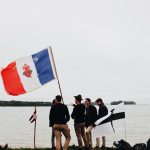 men standing beside pole with flag