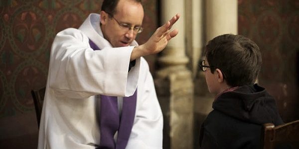 27 novembre 2016 : Le père Augustin DENECK donne le sacrement de réconciliation à un jeune garçon. Paroisse Saint-Ambroise, Paris (75), France.